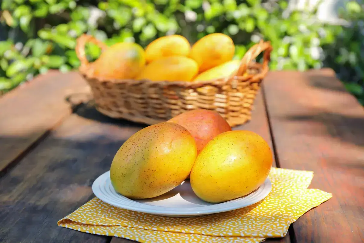 plate-with-tasty-mangoes-on-wooden-table